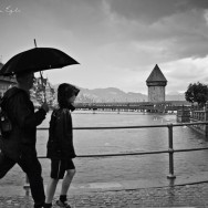 Two people walk with an umbrella past the old bridge in Luzern, Switzerland