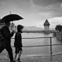 Two people walk with an umbrella past the old bridge in Luzern, Switzerland