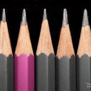 A pink pencil surrounded by grey pencils