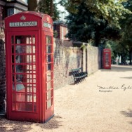 A traditional red phone box in a leafy road in London.