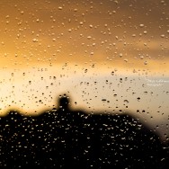 A sunset seen through a window full of raindrops.