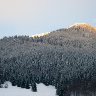 A sunset behind a snow covered mountain.