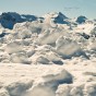 A pile of snow with the Alps in the background.
