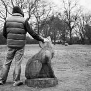 A man with sculpture of a wolf in Regents Park, London.