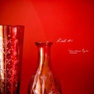 A red vase and a red bottle against a red wall.