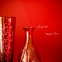 A red vase and a red bottle against a red wall.