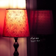 A red table lamp and its reflection in the window.