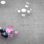 Two men drinking coffee at a pink table taken from a vantage point.