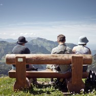 A group of people sit on a bench overlooking the Swiss Alps.