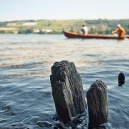 Canoeists glide into the frame of a landscape.