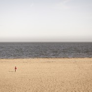 A little boy running towards the waves at a deserted beach.