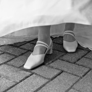 A bride lifts her dress to reveal her wedding shoes.