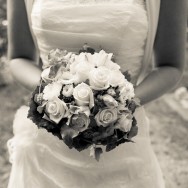 A wonderful bride is holding her beautiful bridal bouquet made from white roses.
