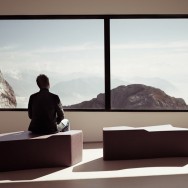 A man looks out upon the Swiss alps from the peak of mount Pilatus.