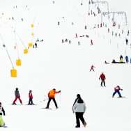 A ski slope in Switzerland full of skiers and snowboarders in colourful clothes.