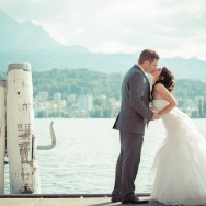 A Bride and Groom kiss on a waterfront pier