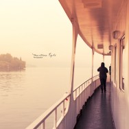 A woman is walking on a boat at sunset.