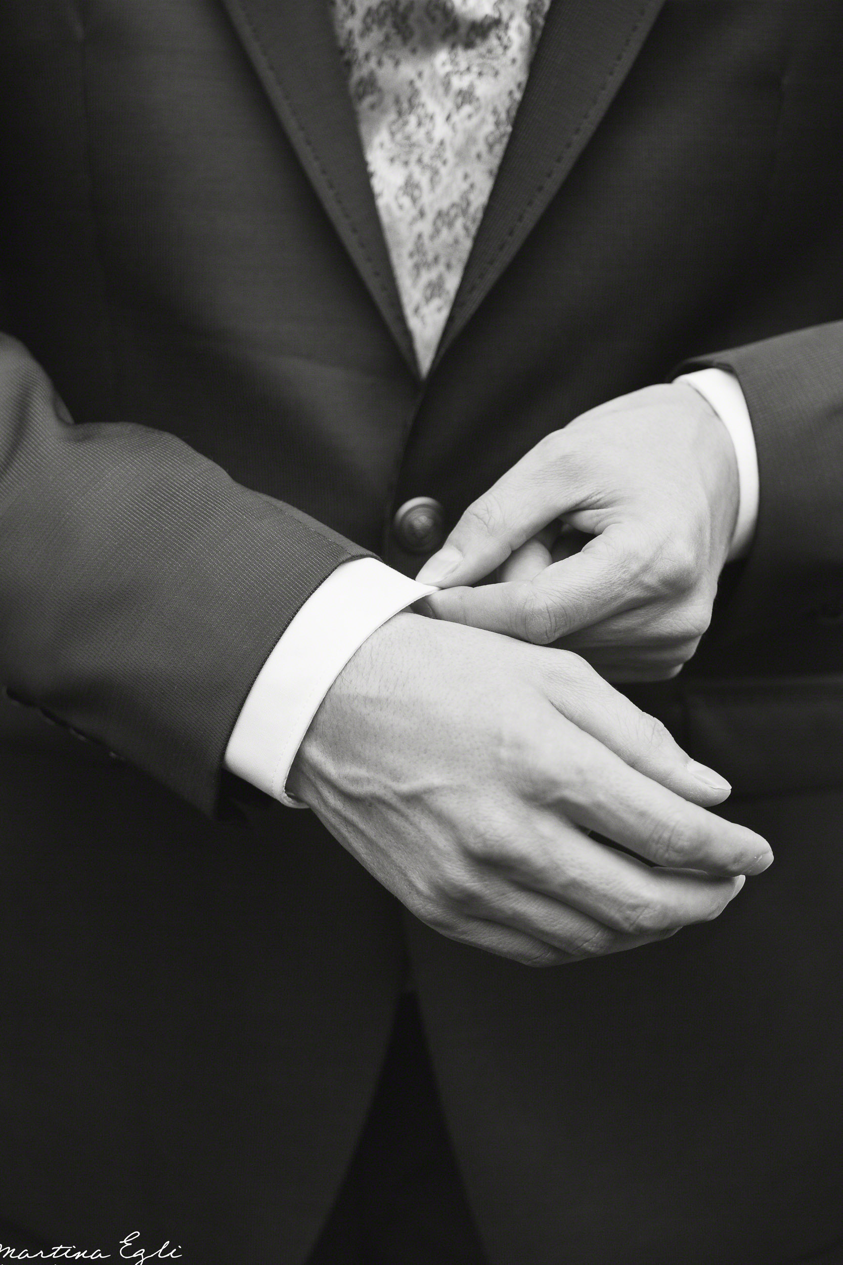 A Groom adjust his cuffs.