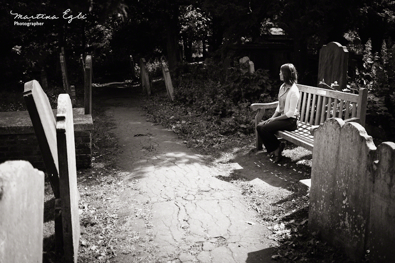 A young woman sits alone in a graveyard.