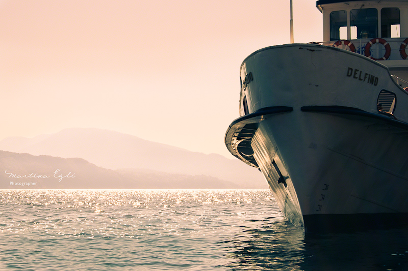 A ship on a lake that is illuminated by the setting sun.