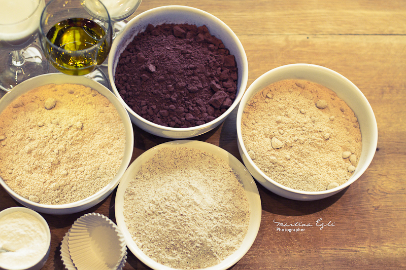 Four bowls full of flour, ground hazelnuts, sugar and cacao powder.