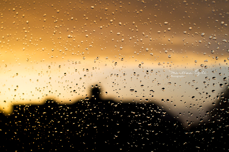 A sunset seen through a window full of raindrops.