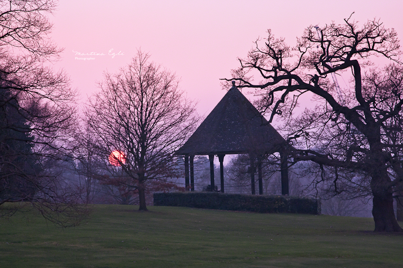The setting sun and a silhouette of a pavilion.