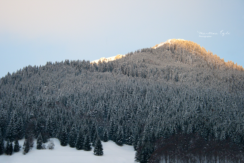 A sunset behind a snow covered mountain.