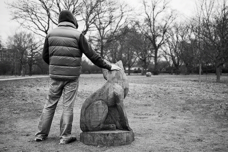 A man with sculpture of a wolf in Regents Park, London.