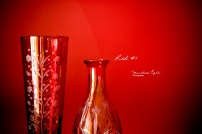 A red vase and a red bottle against a red wall.