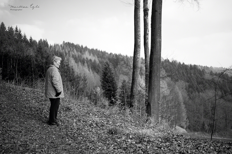 A woman stands still on a mountain ridge, deep in thought.