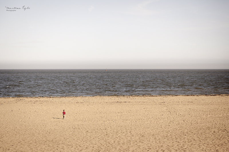 A little boy running towards the waves at a deserted beach.