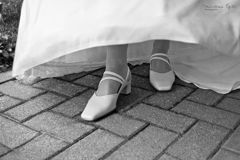 A bride lifts her dress to reveal her wedding shoes.