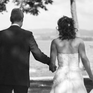 Newlyweds walk hand in hand towards a lake