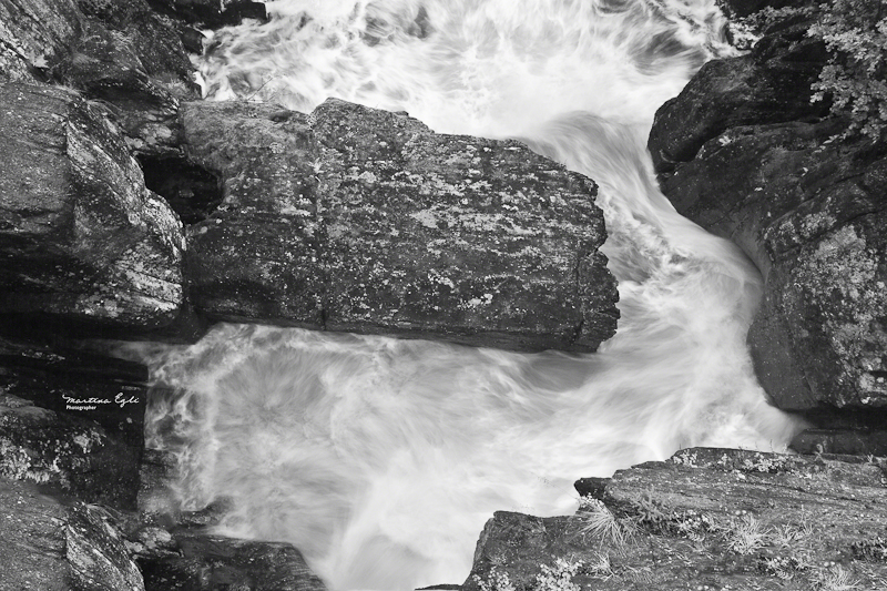 Water is swirling around a rock.