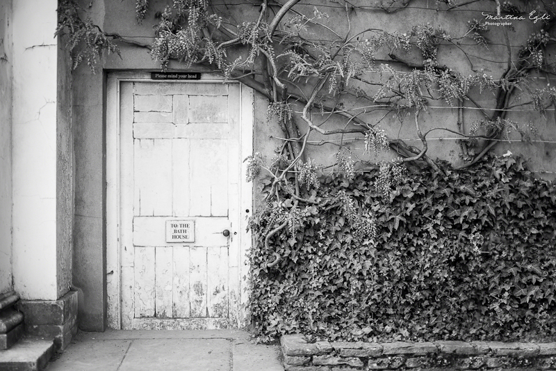 An old door with a sign "To The Bathouse"