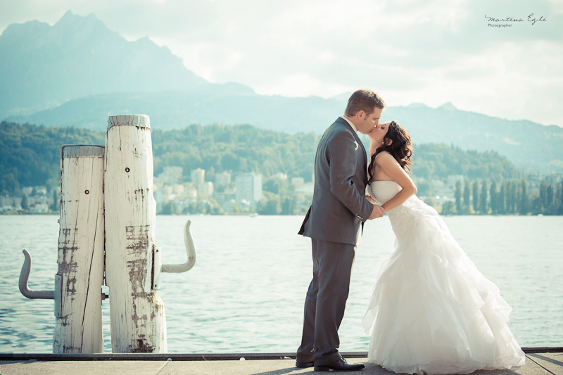 A Bride and Groom kiss on a waterfront pier