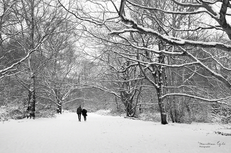 A couple walk in the snow.