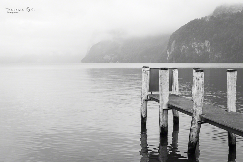 A jetty leading onto a misty lake in Switzerland.